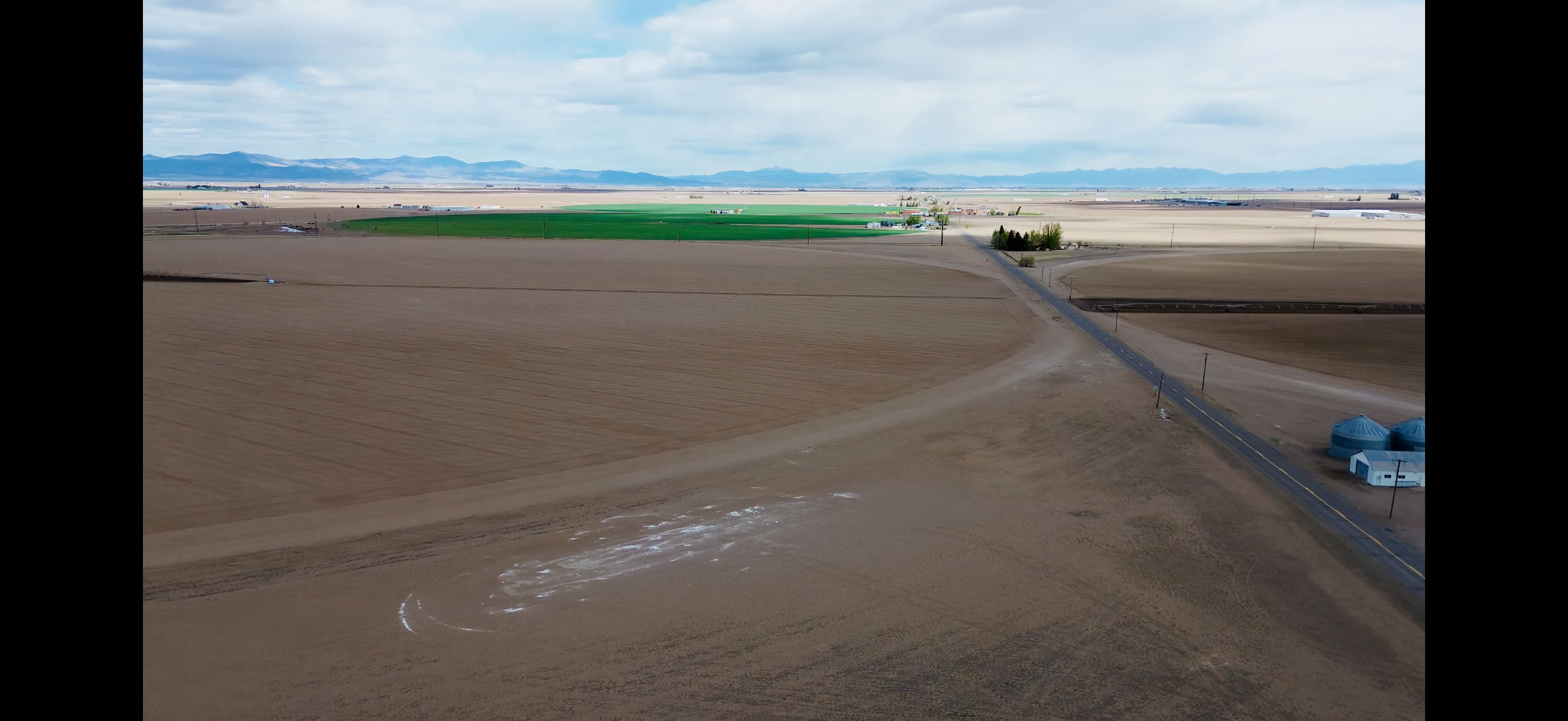 Aerial view of farmland, a county road, and mountains in the San Luis Valley
