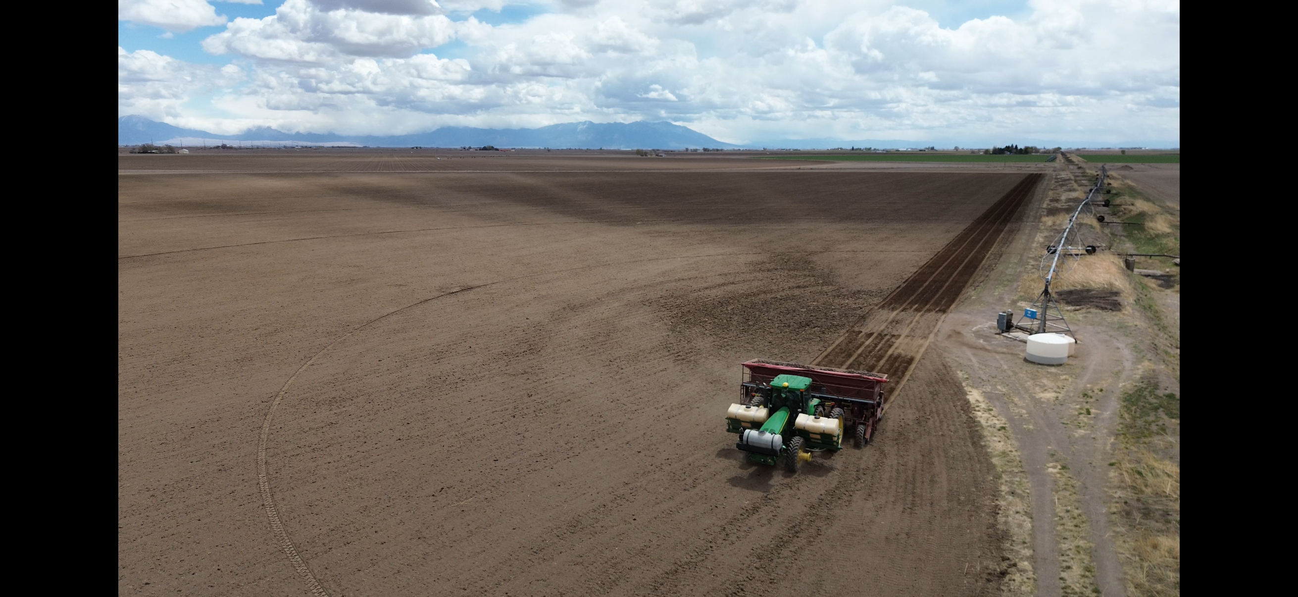 Tractor planting a field in the San Luis Valley with mountains behind